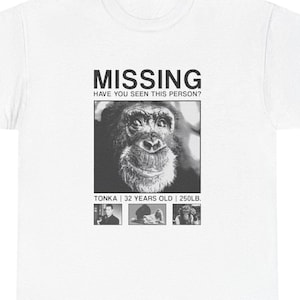 May include: White t-shirt with a black and white graphic of a chimpanzee and the text "MISSING". The graphic includes the text "HAVE YOU SEEN THIS PERSON?" and "TONKA | 32 YEARS OLD | 250LB."