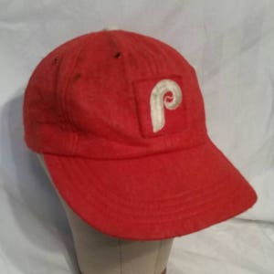 May include: A red baseball cap with a white felt Philadelphia Phillies logo.