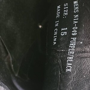 May include: Close-up of the inside of a shoe showing the size, color, and manufacturer information. The text reads "Mens NIA-049 Purple/Black Size: 15 Made in China."
