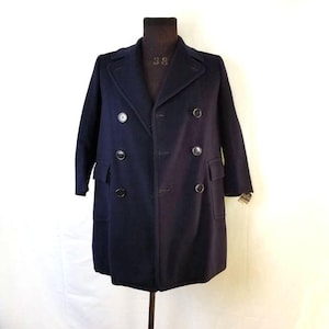 May include: A navy blue double-breasted peacoat with four black buttons. The coat is on a mannequin and has a smooth, textured surface.