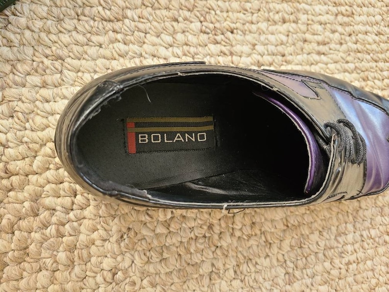 May include: Close-up of the inside of a black leather dress shoe with a purple and black ombre design. The shoe has a black leather insole with the word "BOLANO" printed on it.