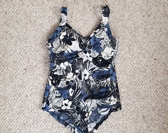 May include: A black and white floral print swimsuit with blue accents. The swimsuit has a scoop neck and adjustable straps.