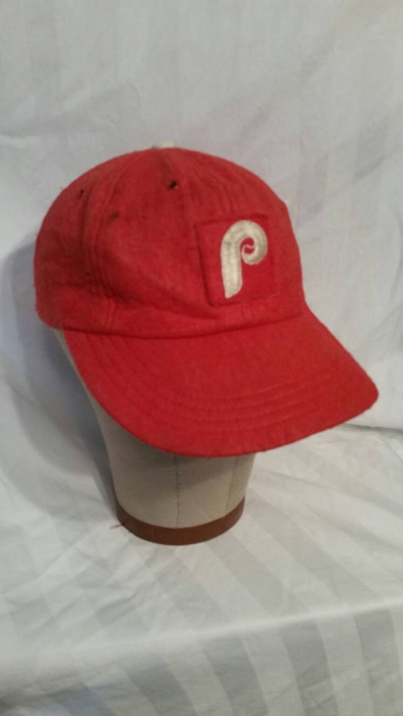May include: A red baseball cap with a white felt Philadelphia Phillies logo.
