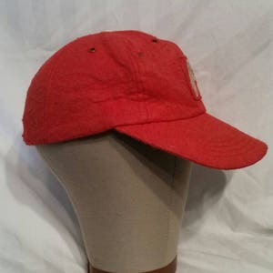 May include: A red baseball cap with a white patch on the front. The patch has a design that is not clear in the image.