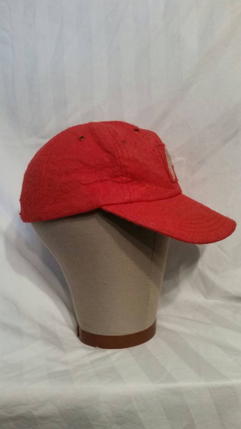 May include: A red baseball cap with a white patch on the front. The patch has a design that is not clear in the image.