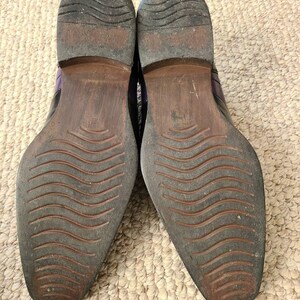 May include: A pair of black leather shoes with purple accents. The shoes have a wavy pattern on the soles.