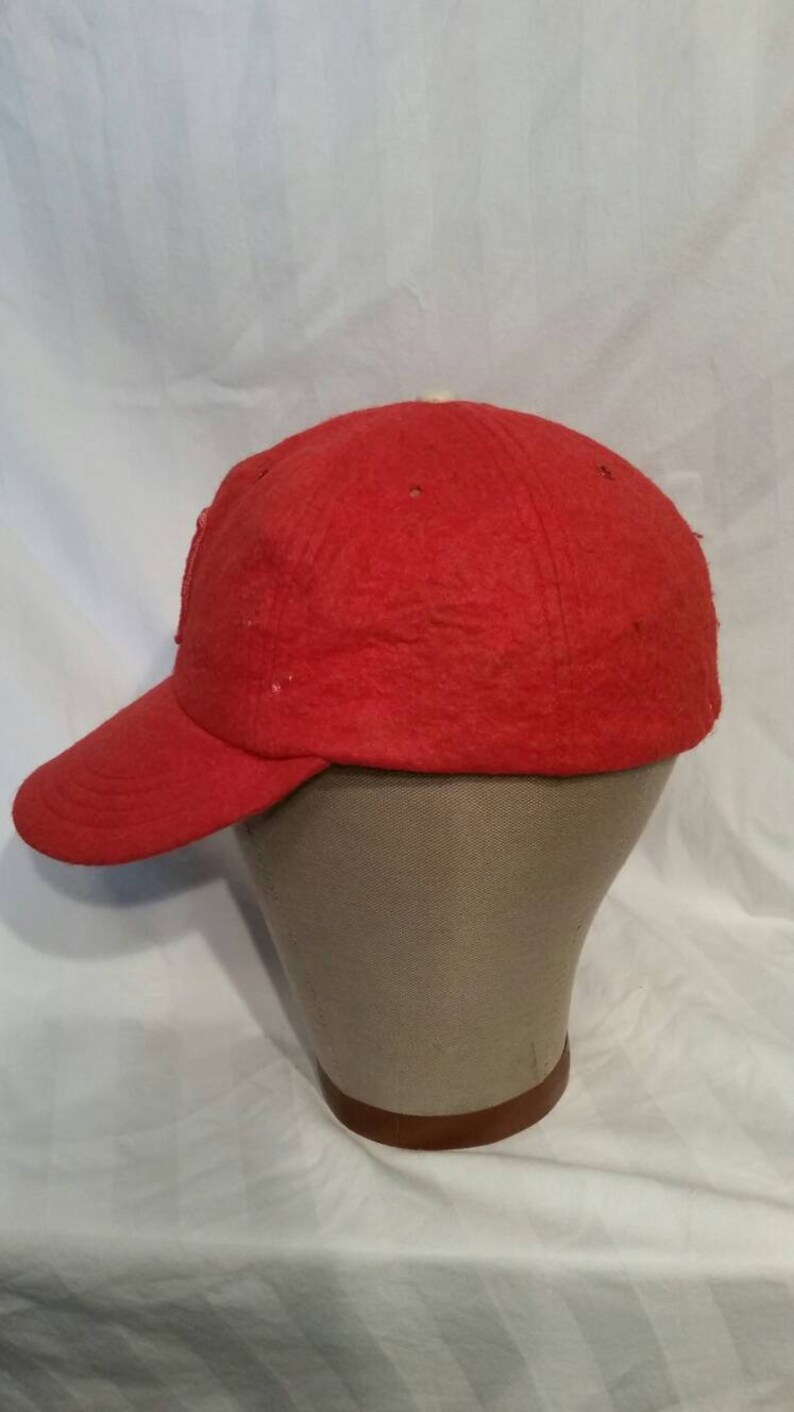 May include: A red baseball cap with a slightly curved brim. The cap is made of a soft, fuzzy material.