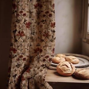 May include: A beige floral curtain with red and brown flower patterns hangs next to a wooden table. Several round loaves of bread sit on the table and a wooden tray. The curtain has a vintage, botanical design.