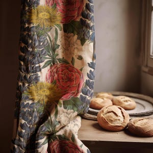 May include: A floral curtain featuring large red, yellow, and blue flowers. The curtain is next to a wooden surface with several round loaves of bread on a plate. The design of the curtain is reminiscent of vintage botanical illustrations.
