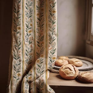 May include: A beige fabric curtain featuring vertical stripes of green foliage and small yellow and blue flowers. The textile displays a repeating botanical pattern with alternating bands of solid yellow and green lines, creating a structured design.