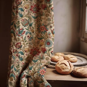 May include: A beige floral curtain with a repeating pattern of red, teal, and blue flowers and leaves. The curtain is draped, revealing a glimpse of a wooden table with several round loaves of bread on a wooden tray.