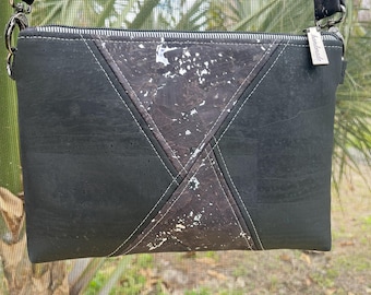 May include: Black crossbody bag with a geometric design. The bag features a central panel with a marbled pattern and white stitching. The zipper is silver, and the bag has a black strap. The tag reads "handmade".