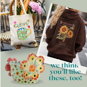 May include: A cream-colored canvas tote bag with a green mug graphic and the text "CUPPA?", a dark brown hoodie featuring a sunflower seed packet graphic on the back, and a light blue ceramic mug with colorful painted flower and dot patterns.