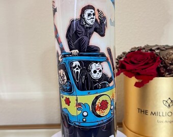 May include: A cylindrical tumbler featuring a cartoon illustration of horror movie characters in a blue and yellow van. The tumbler has the word "END" in white letters at the bottom. The background is a light blue color.