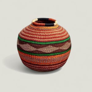 May include: A round, woven basket with a wide opening. The basket features horizontal bands of color, including red, orange, green, and brown. The basket is approximately 10 inches in diameter and 8 inches tall.