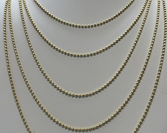 May include: A set of six gold ball chain necklaces of varying lengths, displayed on a white mannequin bust.
