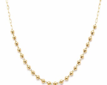 May include: A gold-toned necklace featuring a delicate chain with evenly spaced, small, round, textured beads. The design consists of a series of polished spherical elements linked together, creating a consistent pattern along the length of the chain.
