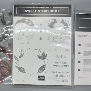 May include: A collection of clear photopolymer stamps and a Big Shot die-cutting machine package. The stamp set includes mushroom, leaf, and mouse illustrations, with text that reads "Sweet Storybook". The Big Shot package is white with black text.