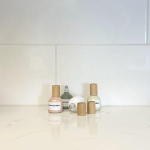 May include: Four glass bottles with wooden caps and labels. The bottles are filled with a clear liquid. The labels read "heart of yellow", "art of", "art of", and "allow".