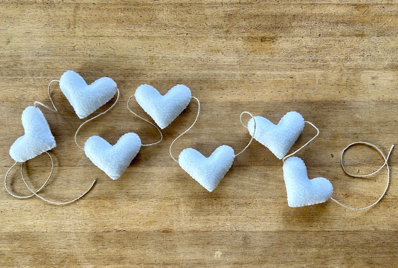 A garland of seven white felt hearts strung together with natural cord.