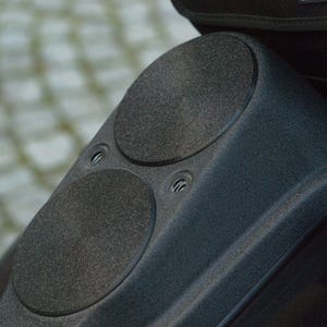 May include: Close-up of a black motorcycle with two round speakers on the back.