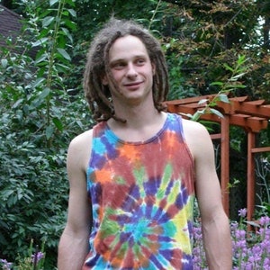May include: A man with long dreadlocks is wearing a tie-dye tank top with a swirling pattern in shades of orange, yellow, blue, green, and purple. The tank top is sleeveless and has a scoop neck.