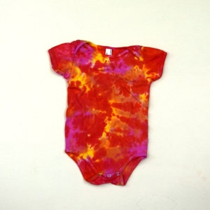 May include: A red, yellow, and pink tie-dye baby onesie with short sleeves.