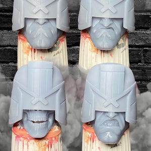May include: Four gray resin busts of a helmeted character, each mounted on a paint bottle. The helmets have a distinctive design with a prominent visor and angular features. The busts are on white and orange paint bottles.