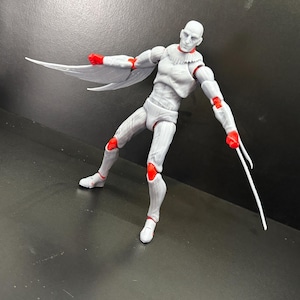May include: A light gray articulated action figure with a bald head and a ruffled collar. The figure features bright red joints at the shoulders, elbows, hips, and knees. It has a large, pointed wing-like blade extending from the right arm.
