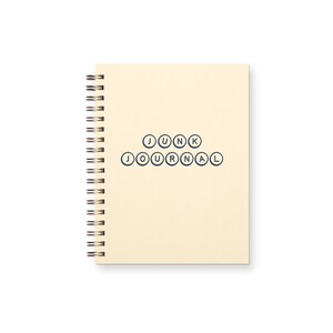 May include: A cream-colored spiral-bound notebook with the words "JUNK JOURNAL" printed in navy blue. The notebook has a copper-colored spiral binding.