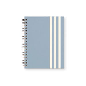 May include: A spiral-bound notebook with a light blue cover featuring three vertical white stripes on the right side. The binding consists of a metallic wire coil along the left edge, securing the front cover to the interior pages of the notebook.