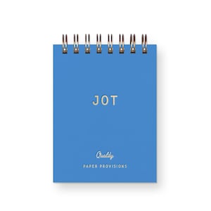 May include: A bright blue spiral-bound notebook featuring the word JOT in gold lettering at the center. Below this, the word Quality is written in a cursive script, followed by the text PAPER PROVISIONS in gold capital letters at the bottom.