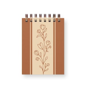 May include: A small spiral bound notebook with a cream colored cover featuring a brown line design and a brown line floral illustration.