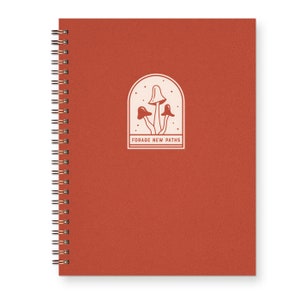 red spiral bound notebook for nature lovers with mushrooms on cover that reads "forage new paths"
