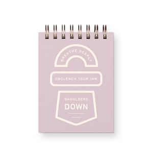 May include: A small, spiral-bound notepad with a pale purple cover. The cover features the phrases "Breathe Deeply," "Unclench Your Jaw," and "Shoulders Down" in a cream color. The notepad has a gold spiral binding.