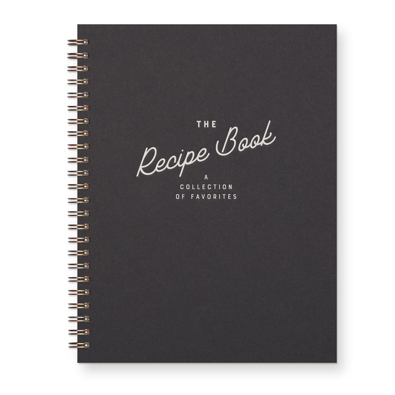 Spiral Bound Keepsake recipe book with a timeless font that reads "The Recipe Book A Collection Of Favorite." The book is black with white text.