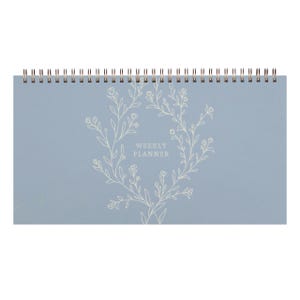 May include: A light blue weekly planner with a white floral design and the text "Weekly Planner" in the center.