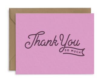 May include: A pink greeting card with the words "Thank You so much" in a dark purple script. The card is inside a brown envelope. The card is a simple and elegant design.