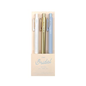 May include: A set of three gel pens in a box labeled "The Bridal." One pen is white with "I DO" printed on it, one is gold, and the third is light blue with "SOMETHING BLUE" printed on it. The box is beige.