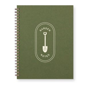 May include: A spiral-bound notebook with a dark green cover. The cover features a white oval design with the words "GARDEN NOTES" and a shovel illustration. The spiral binding is gold-colored.