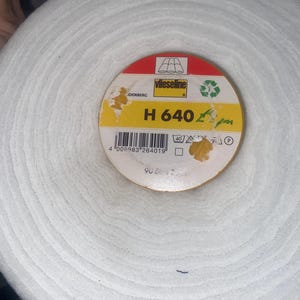 May include: A roll of white fabric with a circular label. The label reads "Vlieseline" and "H 640". The roll is 90 cm wide. The fabric appears to be a batting or interfacing material.