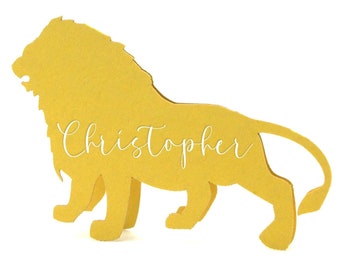 May include: A yellow lion-shaped cutout standing on four legs with a long tail. The name Christopher is written in white cursive script across the center of the lion's body. The object is presented against a plain white background.