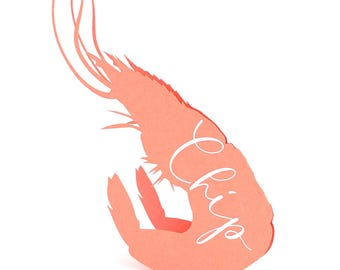 May include: A coral-colored paper shrimp with the word "Chip" written in cursive script. The shrimp is cut out with detailed edges and is set against a white background. The design is simple and elegant.