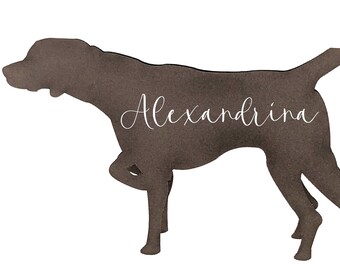 May include: A brown silhouette of a dog in a hunting pose, with the name "Alexandrina" in cursive script. The dog is depicted with its front leg raised, tail up, and head forward, set against a white background.