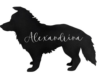 May include: Black silhouette of a dog with the name "Alexandrina" in cursive script. The dog is depicted in a side profile, with a fluffy coat and a long tail. The background is plain white.