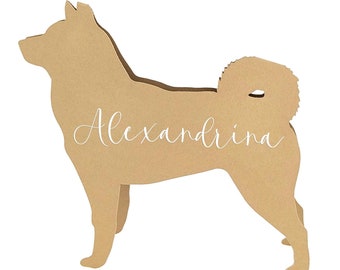 May include: A tan-colored wooden cutout in the shape of a dog, with the name "Alexandrina" written in cursive. The dog is standing with its tail curled and ears perked up. The cutout is on a white background.