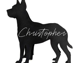 May include: A black silhouette of a dog, likely a Great Dane, standing on a white background. The dog's name, "Christopher," is written in cursive across its side. The dog is cut from a solid material.