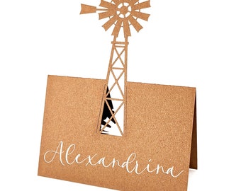 May include: A brown card with a windmill cutout and the name "Alexandrina" in white script. The windmill design is a light brown color and is attached to the top of the card. The card is folded in half.