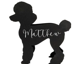 May include: A black poodle-shaped cutout with the name "Matthew" in white script. The dog silhouette is standing, with a fluffy tail and a distinctive poodle haircut. The background is plain white.