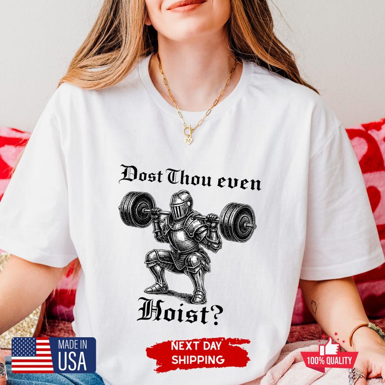 May include: White t-shirt with a black and white illustration of a knight lifting weights, with the text "Dost Thou even Hoist?" The shirt also has a "Made in USA" label.